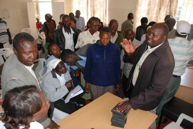 Area Chief Fred Killy hands out DVDs provided by the British High Commission to Burnt Forest residents