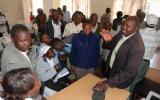 Area Chief Fred Killy hands out DVDs provided by the British High Commission to Burnt Forest residents